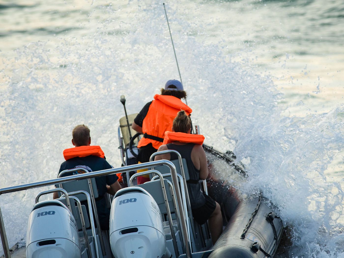 Twin Suzuki 100 outboards on the transom of a rigid inflatable boat, spray flying behind the crew